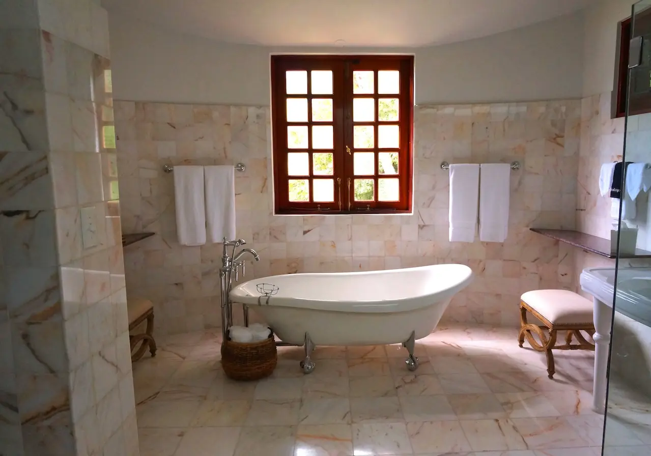 Bathroom with a freestanding tub, stone tile walls and a wood-framed window